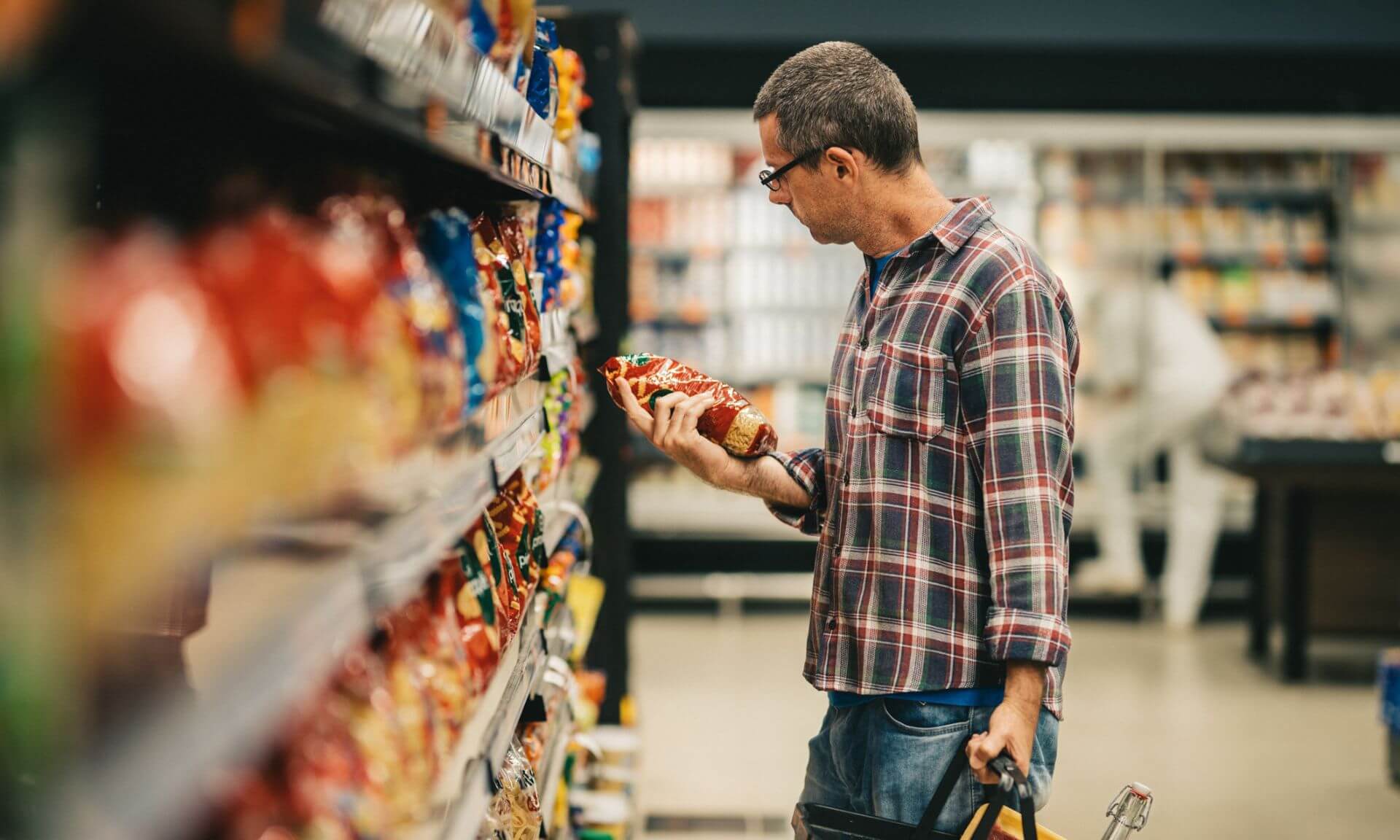 Un homme choisit un paquet à l’épicerie.