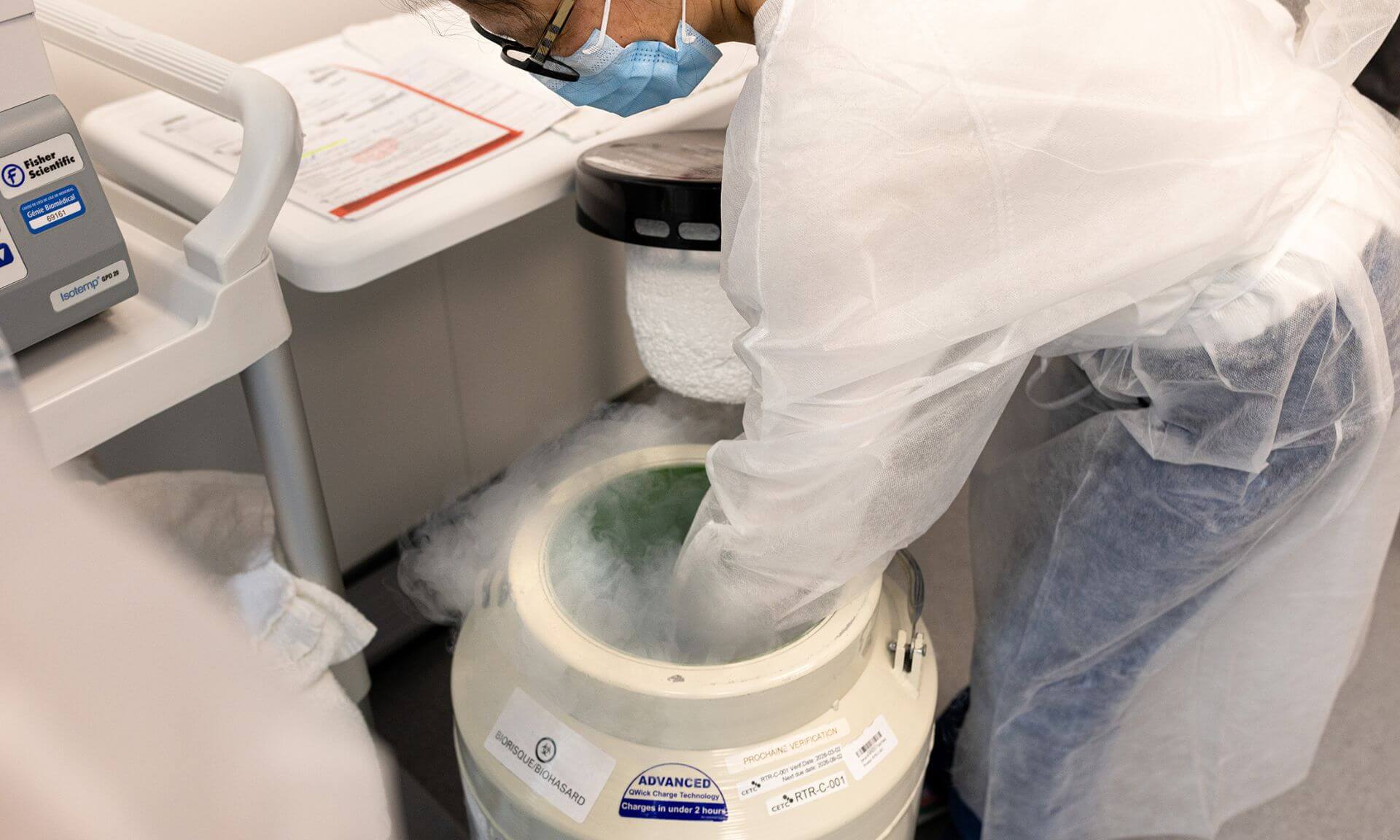 Un technologiste du laboratoire de thérapie cellulaire manipule une cuve de transport de produits cellulaires contenant de l'azote liquide.