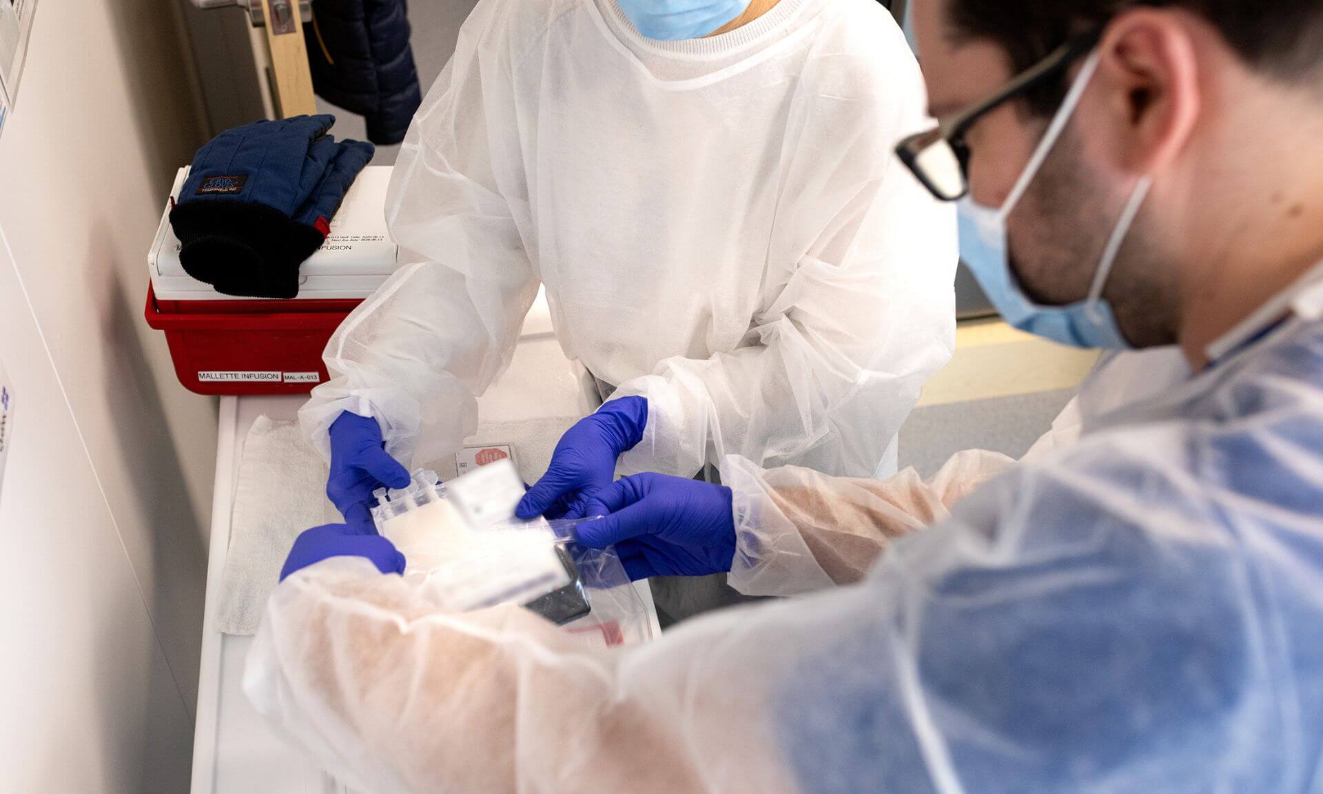 Transmission d'un greffon cellulaire du personnel du laboratoire de thérapie cellulaire à l'infirmier Francis Delisle qui va l'administrer au patient.
