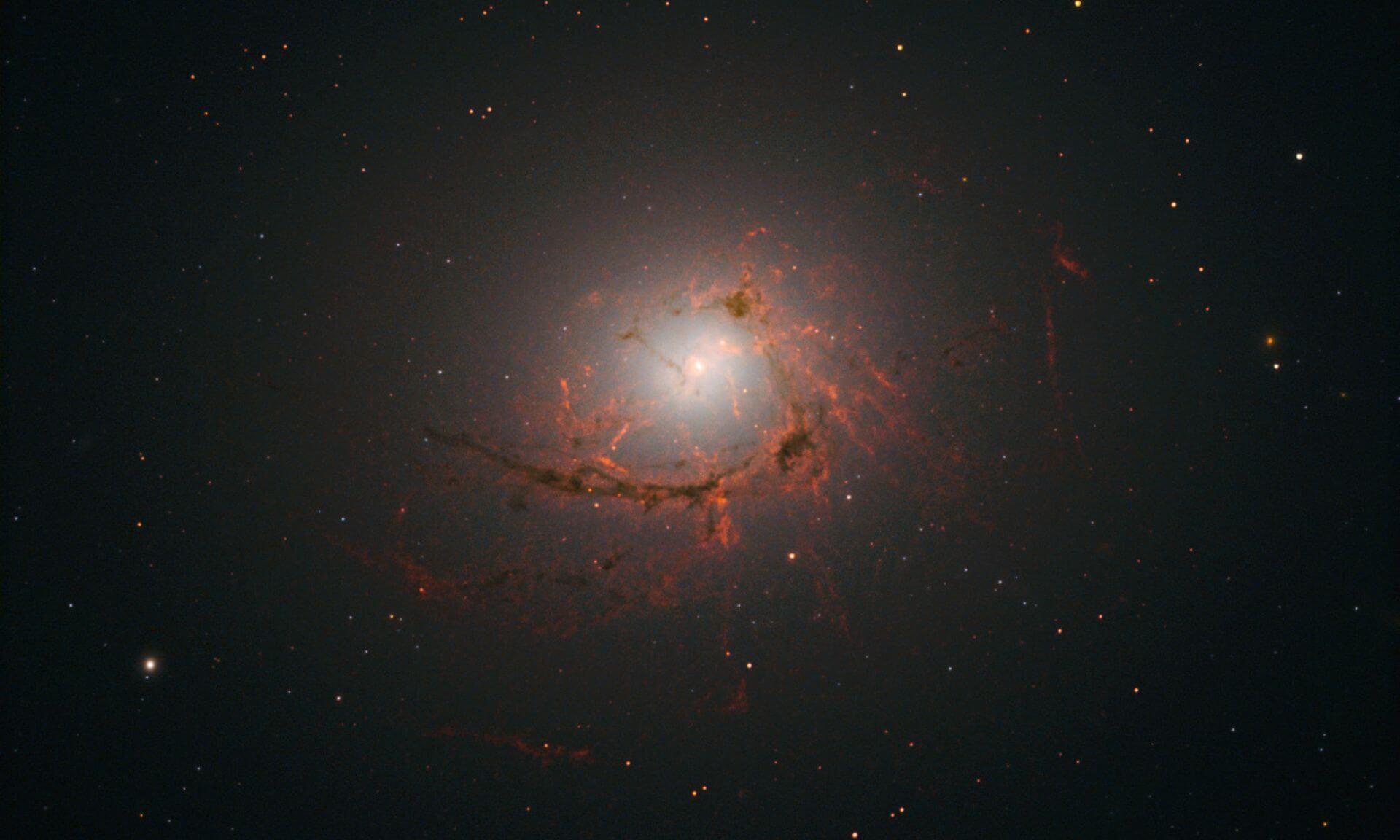 An image of elliptical galaxy NGC4696 located at the center of the Centaurus Cluster taken by the Hubble Space Telescope. This image shows dusty filaments surrounding the center of the galaxy. 