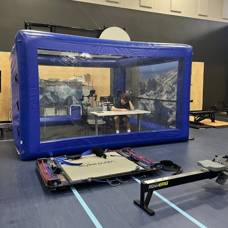 La tente bleue est une chambre hypoxique de l’Institut national du sport du Québec, où des générateurs modifient l’air ambient de façon à reproduire une altitude de 3500 mètres.