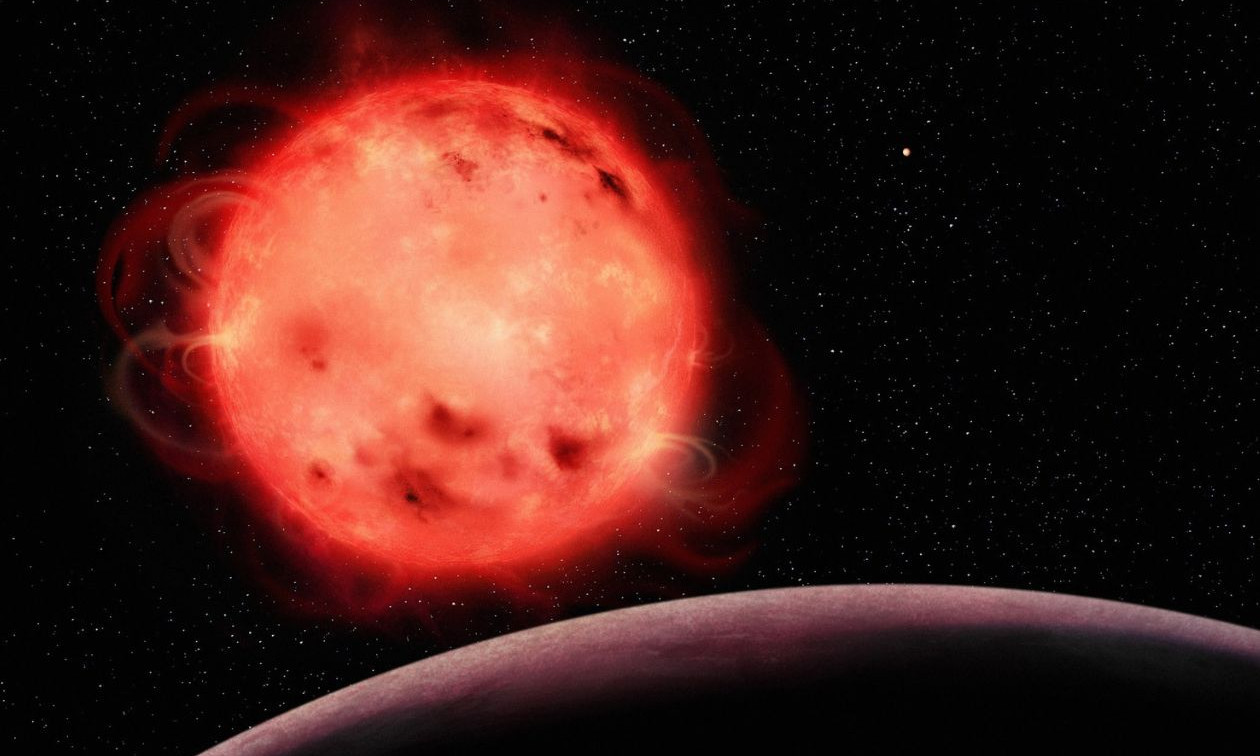 Cette représentation artistique de l'étoile naine rouge TRAPPIST-1 met en évidence sa nature très active. L'étoile semble avoir de nombreuses taches stellaires (des régions plus froides de sa surface, semblables aux taches solaires) et des éruptions. L'exoplanète TRAPPIST-1 b, la planète la plus proche de l'étoile du système, est visible au premier plan, sans atmosphère apparente. L'exoplanète TRAPPIST-1 g, l'une des planètes de la zone habitable du système, est visible à l'arrière-plan, à droite de l'étoile. Le système TRAPPIST-1 contient sept exoplanètes dont la taille est semblable à celle de la Terre.