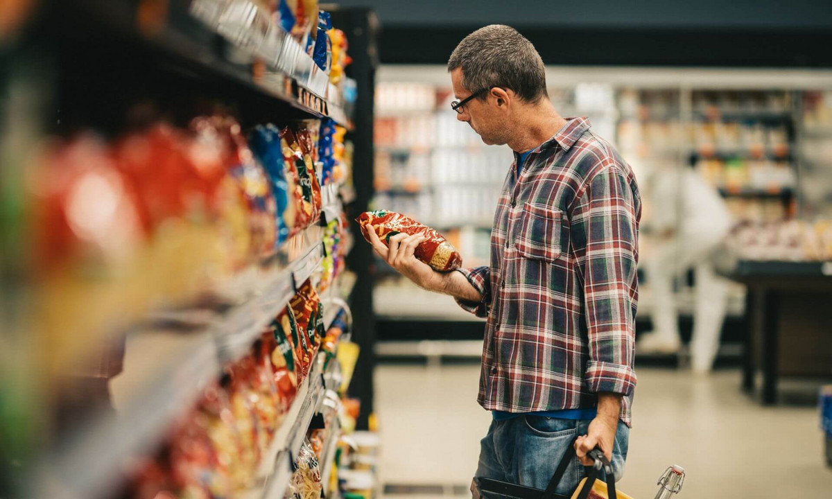 Un homme choisit un paquet à l’épicerie.