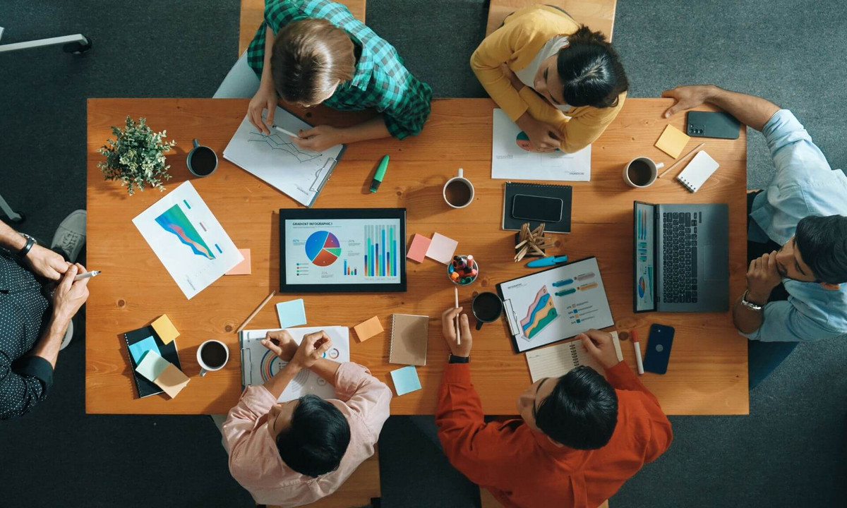 Une équipe de travail est réunie autour d'une table et de documents pour une session de travail