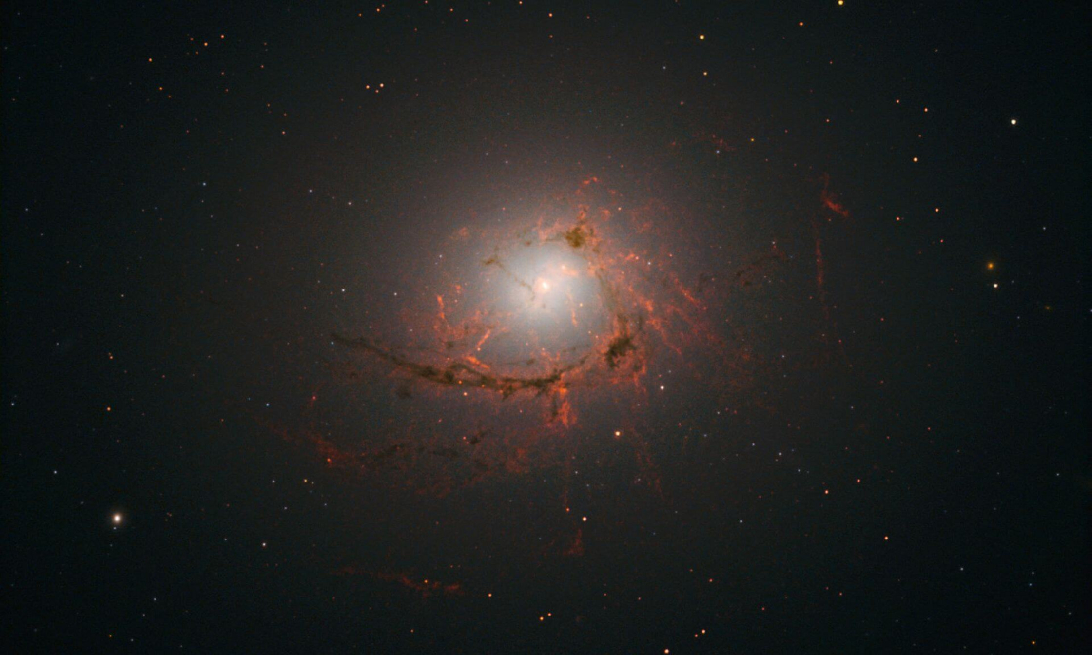 An image of elliptical galaxy NGC4696 located at the center of the Centaurus Cluster taken by the Hubble Space Telescope. This image shows dusty filaments surrounding the center of the galaxy. 