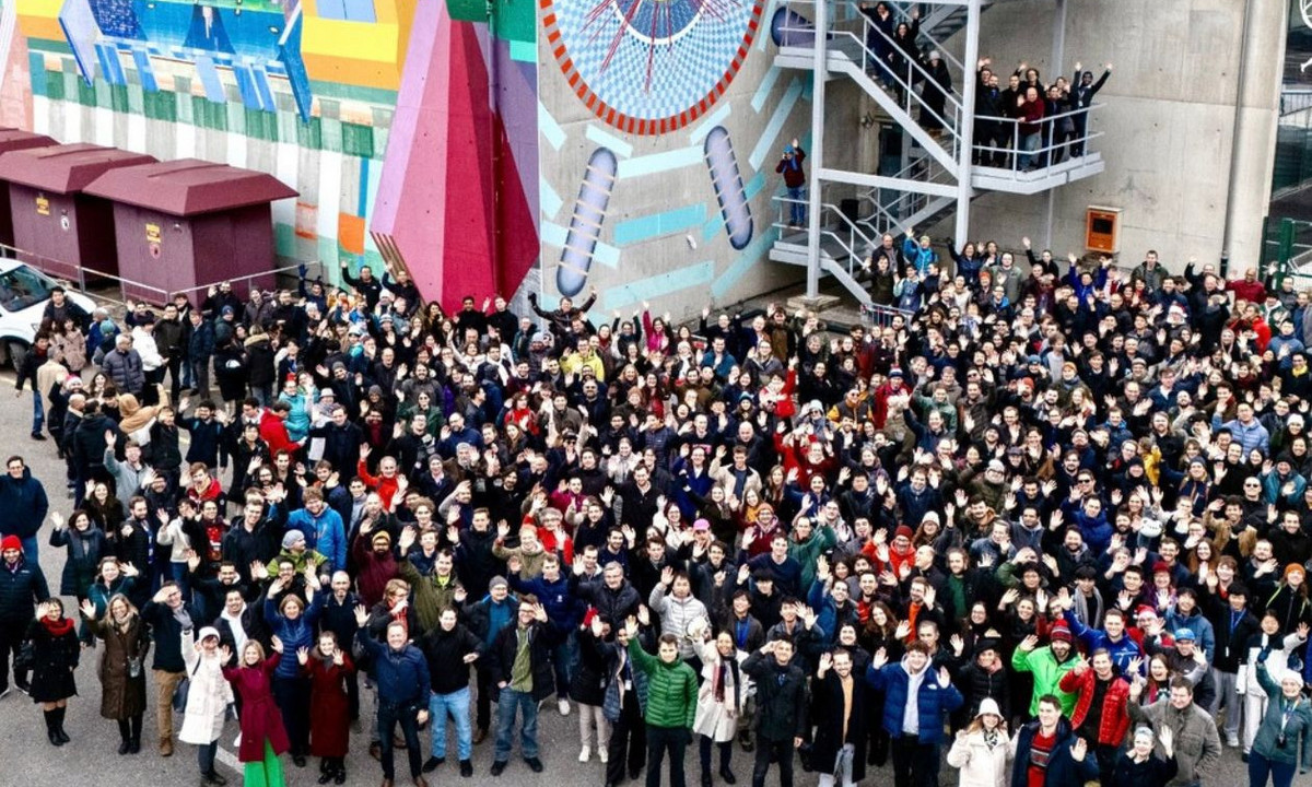 Membres du project ATLAS devant une fresque murale du détecteur ATLAS, au CERN, à la frontière franco-suisse.
