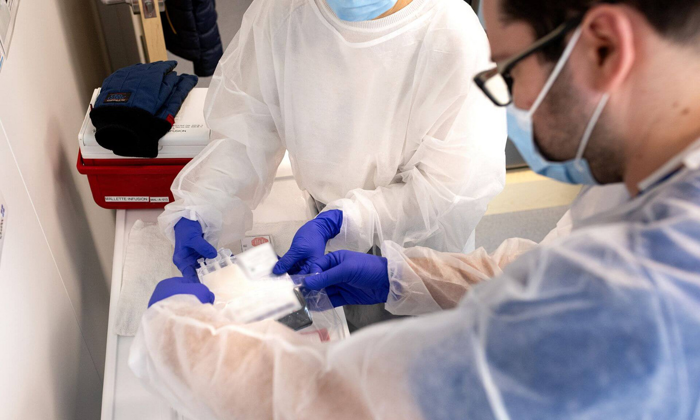 Transmission d'un greffon cellulaire du personnel du laboratoire de thérapie cellulaire à l'infirmier Francis Delisle qui va l'administrer au patient.
