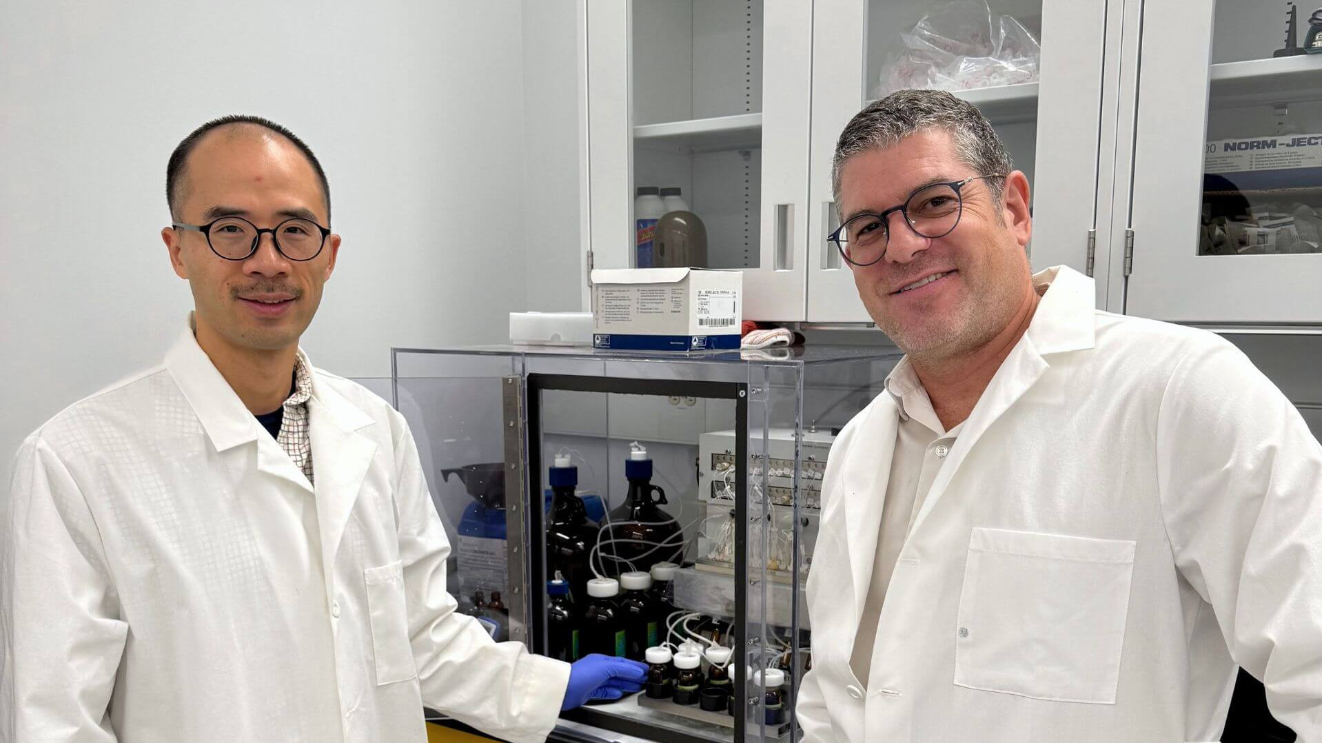 Les chercheurs Alexis Vallée-Bélisle (à droite) et Guichi Zhu (à gauche) en train de synthétiser des cascades de signalisation à l'aide d'un synthétiseur d'ADN.