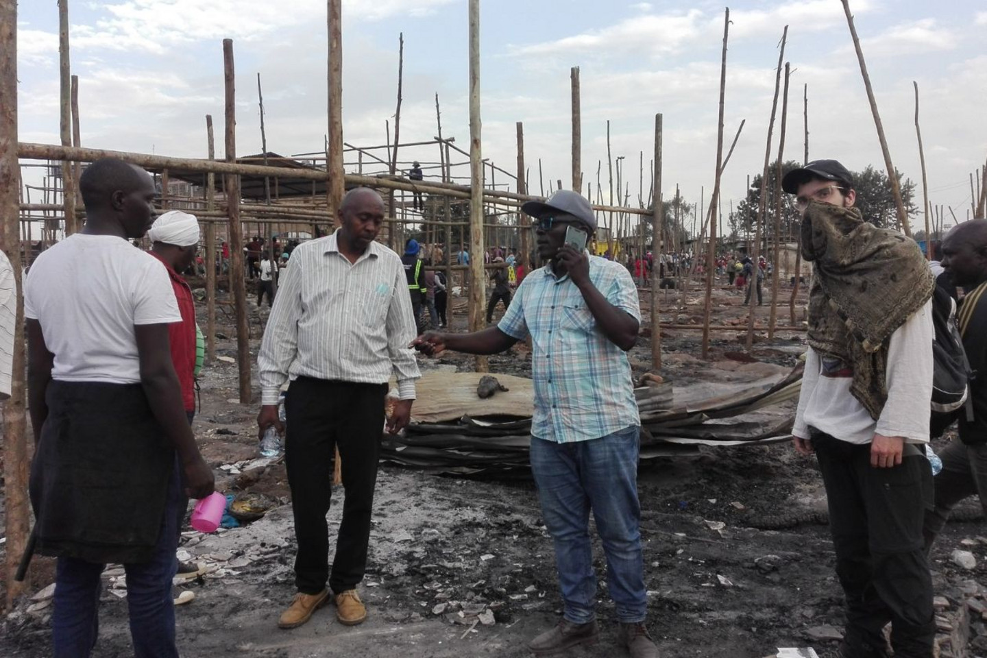 Zy St-Pierre-Bourdelais, de la Jeune coopérative d'architecture humanitaire Kaza (à droite), en présence de membres de la communauté du marché détruit, ainsi que des bénéficiaires du projet de logements à coût minimal.