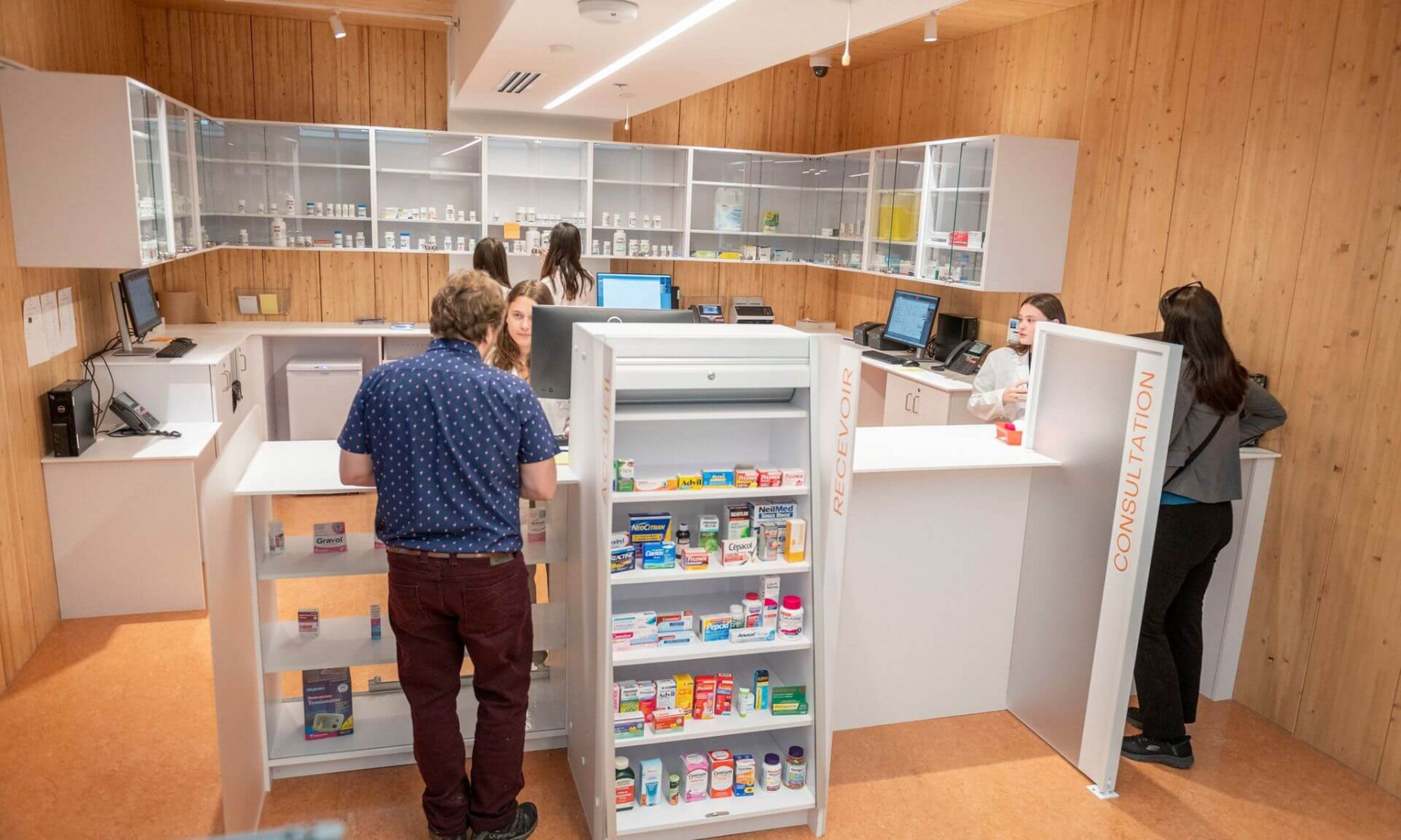L'intérieur d'une pharmacie, avec un comédien et une comédienne à l'œuvre.