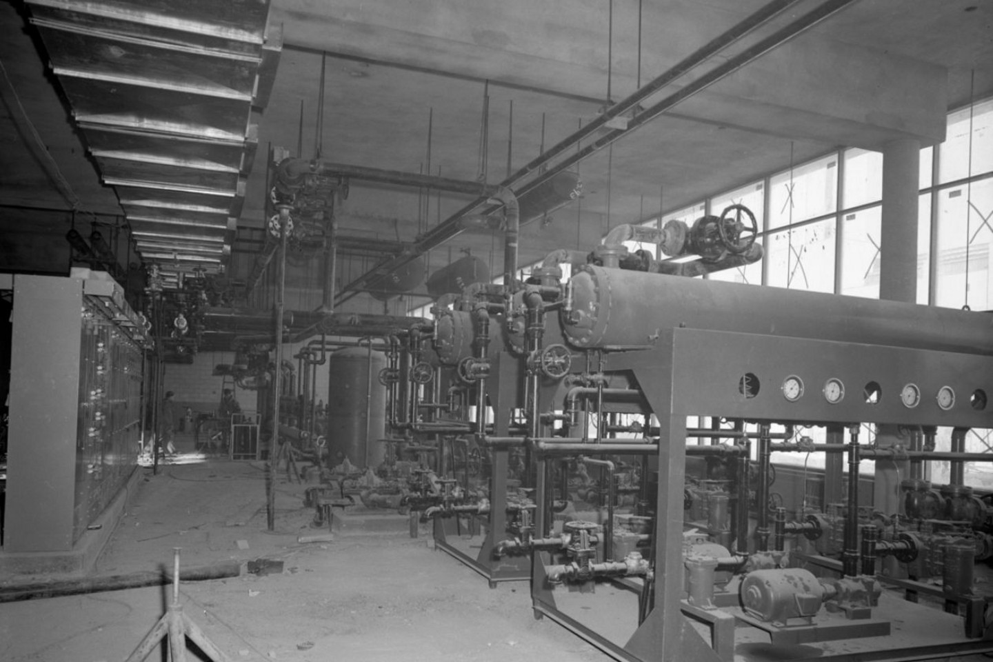 Construction de la centrale thermique (vue intérieure), où l’on voit les anciennes installations d’échangeurs. Ces derniers utilisent l'eau chaude haute température pour réchauffer l'huile lourde, ancien combustible que le gaz naturel et l’électricité ont remplacé avec le temps, décembre 1963 / Photographie: Service de polycopie. Centrale de photographie. 